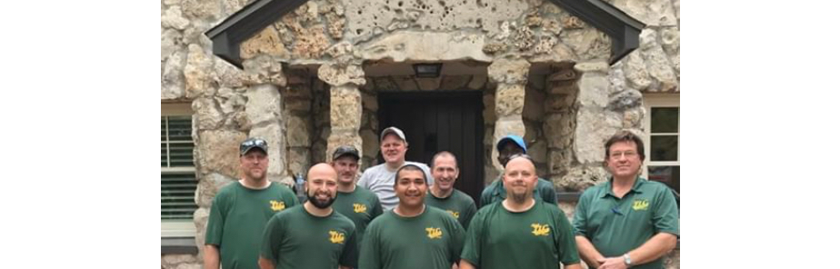 Team members in matching green shirts standing in front of stone building entrance