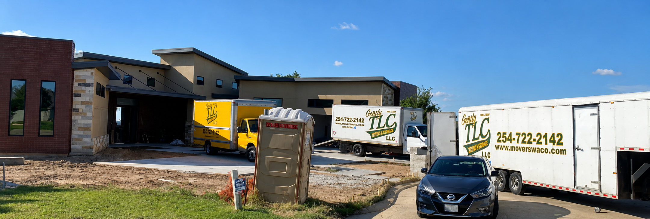 TLC moving company trucks and equipment parked at commercial building under construction